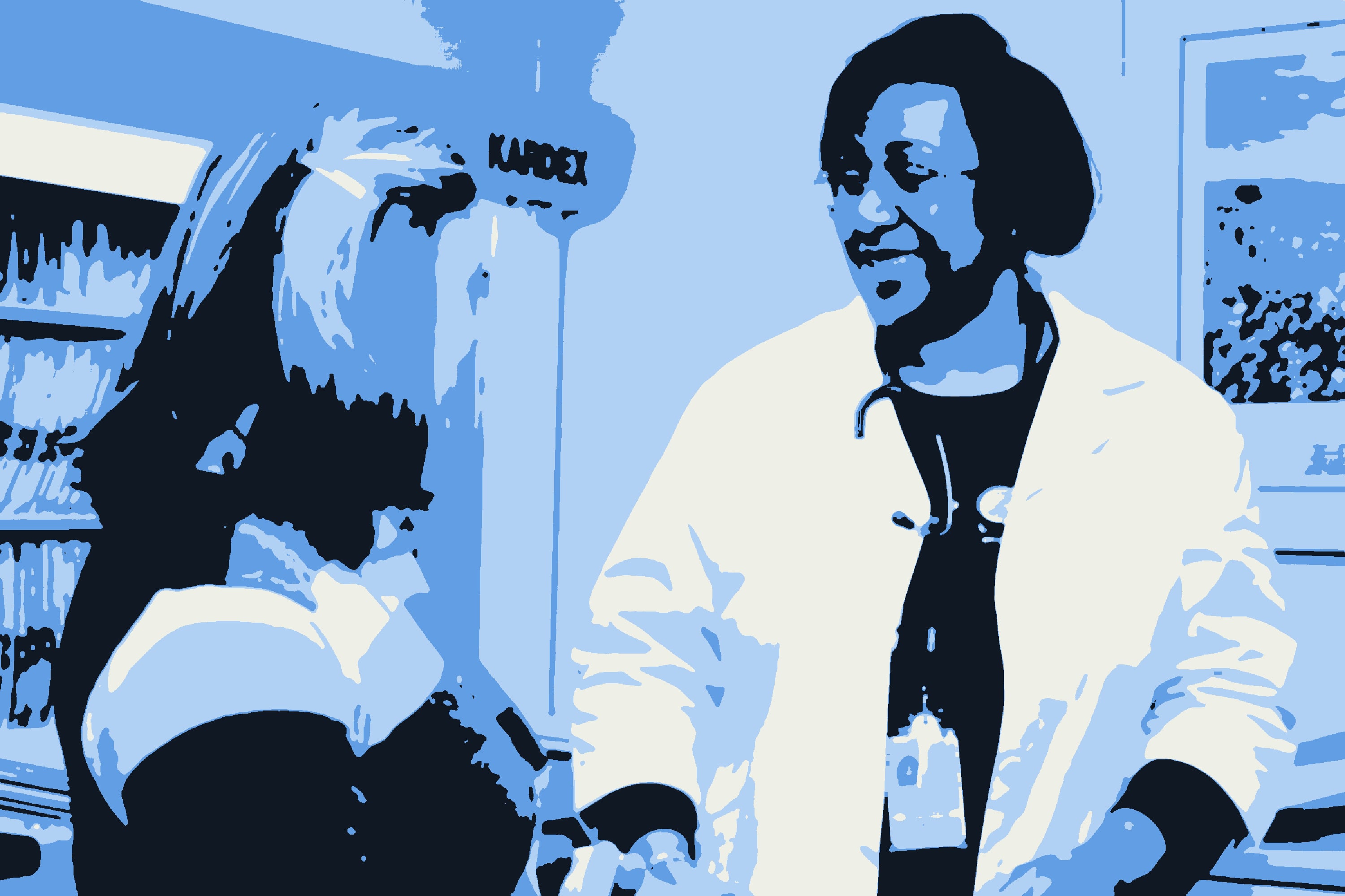 A physician in a white coat and stethoscope talking with a colleague beside a rack of patient files