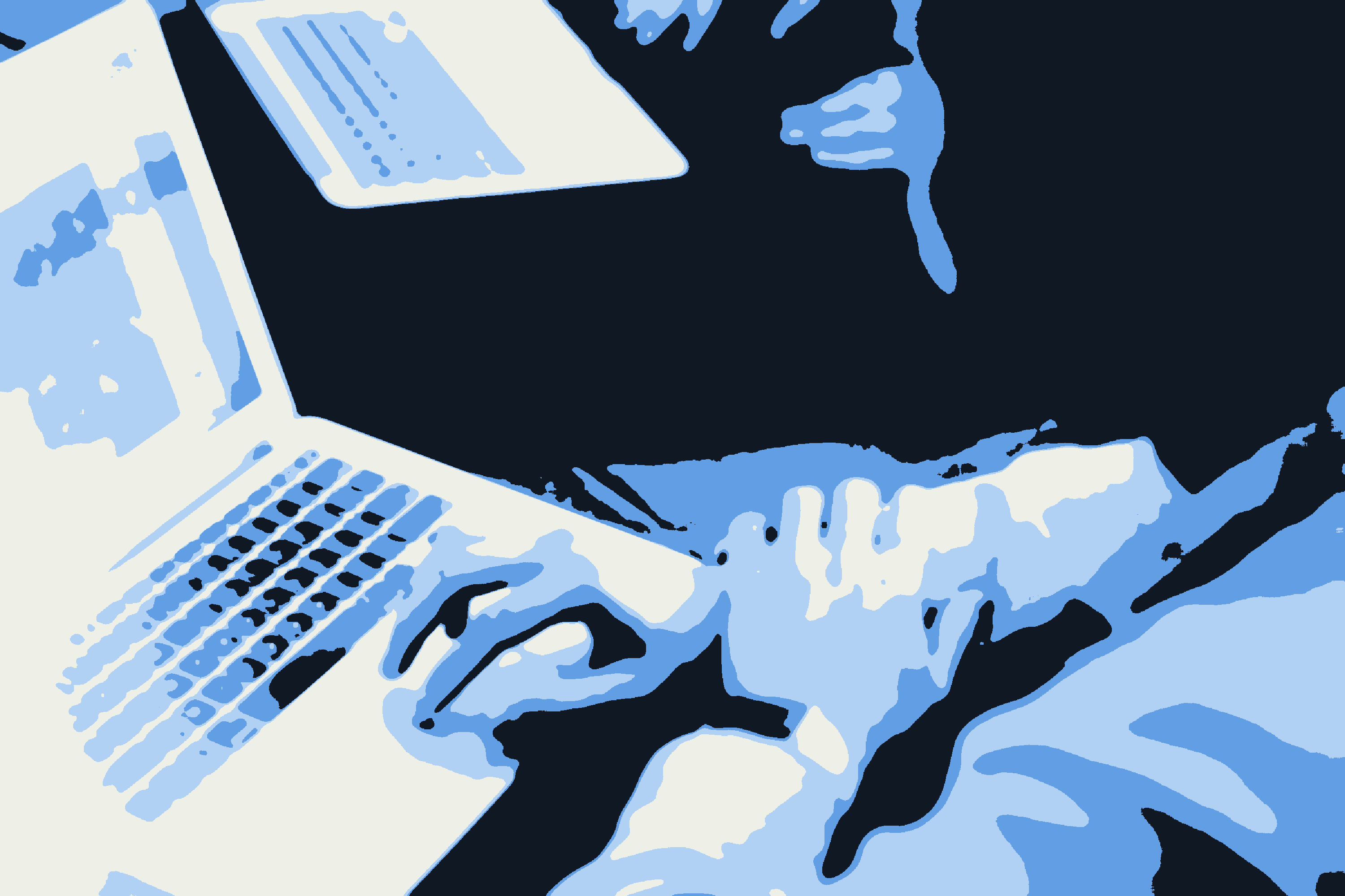 Two people working on laptops at a shared desk, one typing.